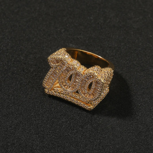 Yellow gold plated iced out "100" numeric ring, full pave baguette and round moissanite stones, bold hip hop bling ring for men shot on dark background