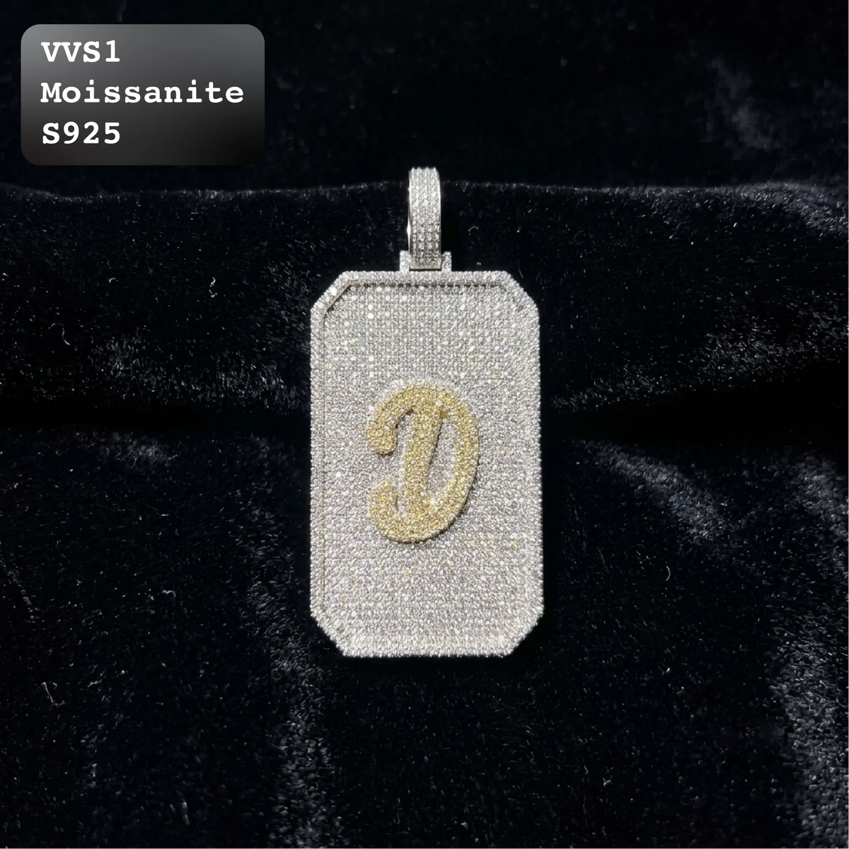 A rectangular moissanite pendant with a gold-colored letter 'D' monogram, displayed on a black velvet surface. A text overlay in the top-left corner reads 'VVS1 Moissanite S925'.