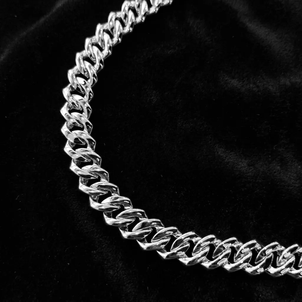 Curved shot of polished plain silver cuban link chain, smooth solid metal links without gemstones, minimalist heavy streetwear hip hop chain texture