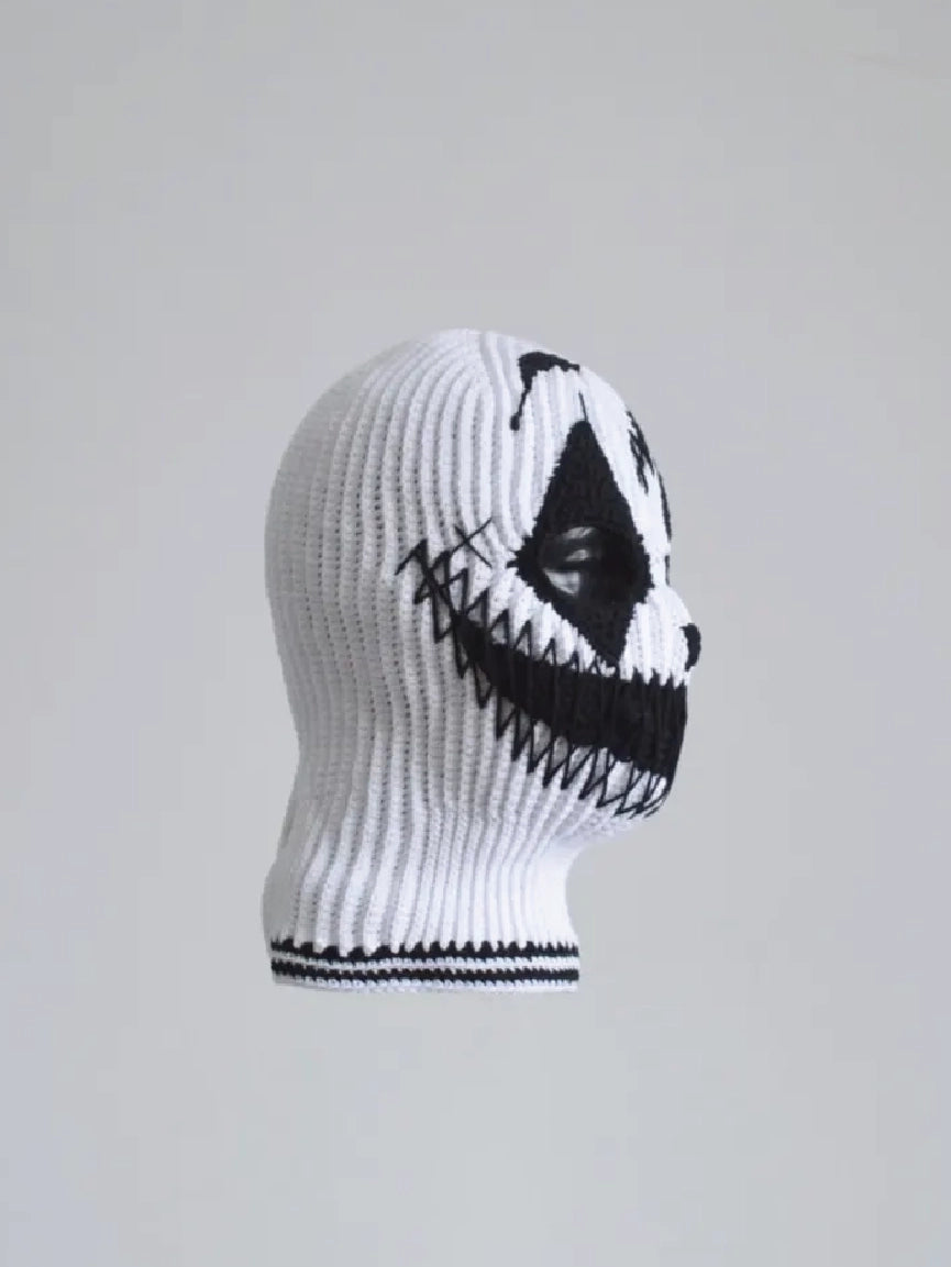 Side profile photo of white ribbed knit balaclava featuring black stitched jagged grimace pattern, scary streetwear ski mask on mannequin head, minimalist grey background