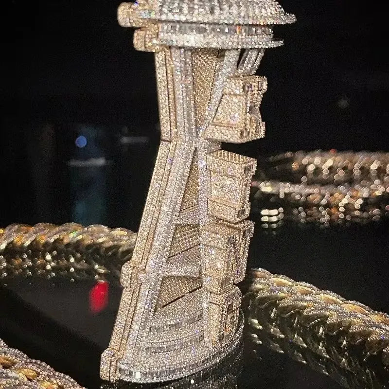 A close-up of a heavily embellished jewelry piece covered in sparkling clear stones, standing upright on a dark reflective surface with other chain jewelry blurred in the background.