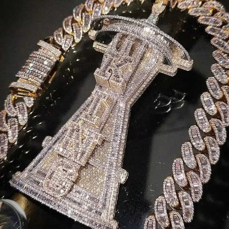 A close-up of a heavily embellished jewelry set featuring a large, intricately paved silver-toned pendant or brooch at the center, surrounded by matching chain bracelets with clear stones on a dark reflective surface.