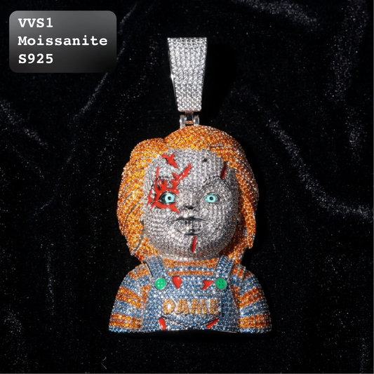 A Chucky moissanite pendant on a black velvet background, featuring a silver bail. The pendant is covered in clear moissanite crystals, depicting Chucky with orange hair, a gray face with red scratches, and a blue and orange striped shirt with 'DAME' written on it.