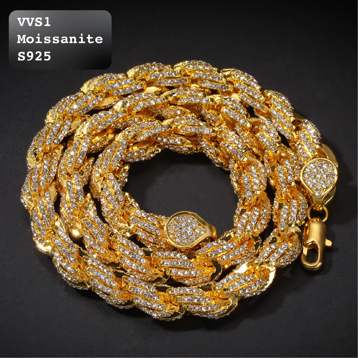 A thick gold-tone Cuban link chain bracelet, coiled on a dark background. The chain is heavily embellished with small clear rhinestones/crystals across all links, with a heart-shaped crystal detail on the clasp and a lobster clasp visible on the right.