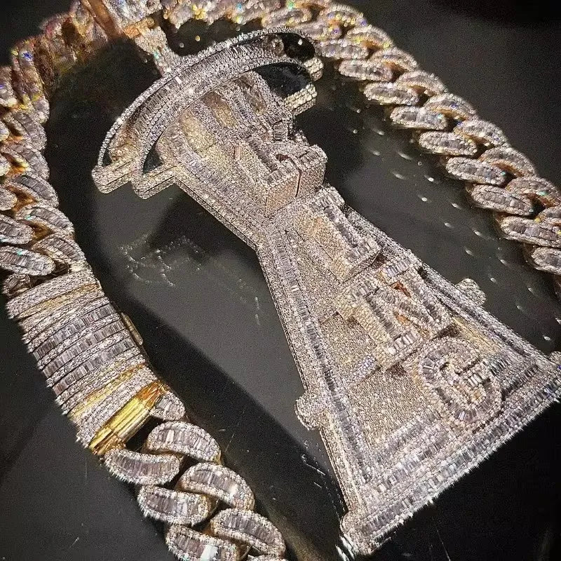 A close-up of a heavily embellished silver-toned pendant and matching chain covered in clear stones, displayed on a dark reflective surface.