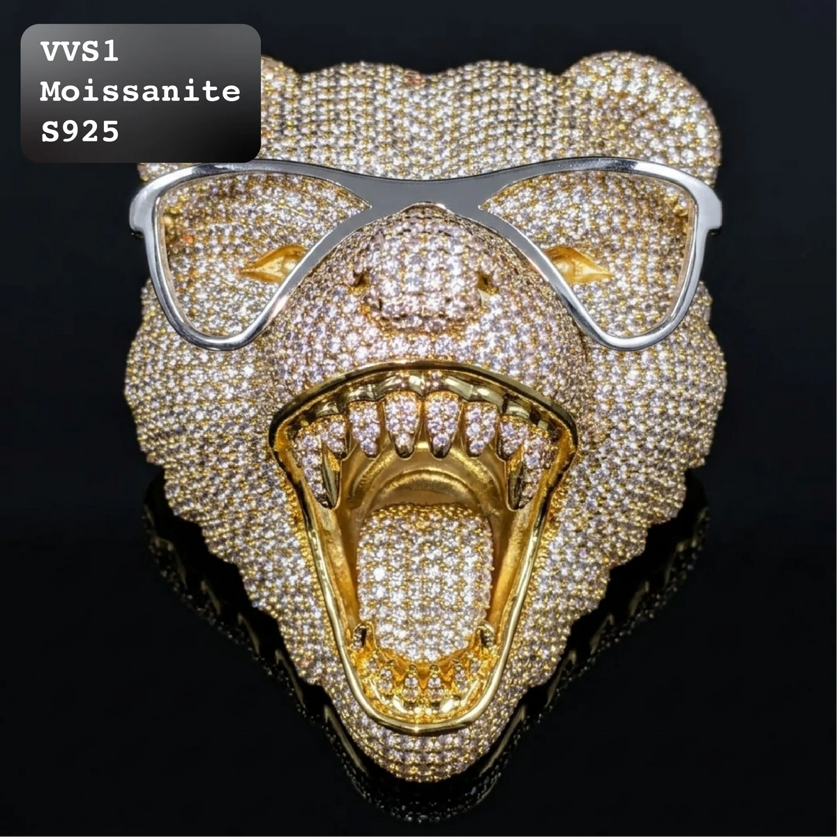 A roaring lion head brooch or pin covered in pavé stones, with a gold-toned open mouth and silver-toned glasses, shown on a black reflective background. Text in the top-left reads 'VVS1 Moissanite S925'.