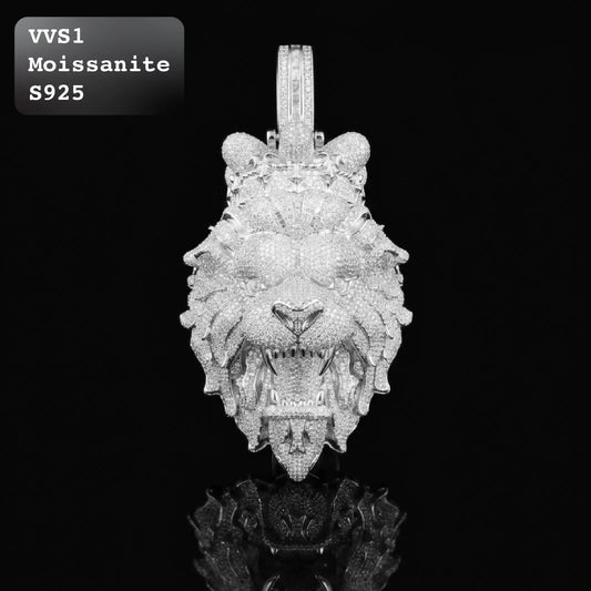A highly detailed lion head pendant encrusted with sparkling clear stones, displayed against a solid black background. A text overlay in the top-left corner reads 'VVS1 Moissanite S925'.