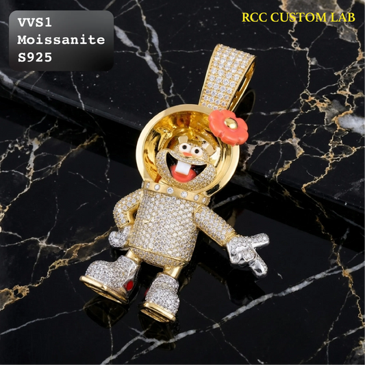A gold astronaut pendant covered in clear pavé stones, featuring a smiling face, red flower on the helmet, and silver-colored hands and feet, displayed on a black marble background with text overlays.