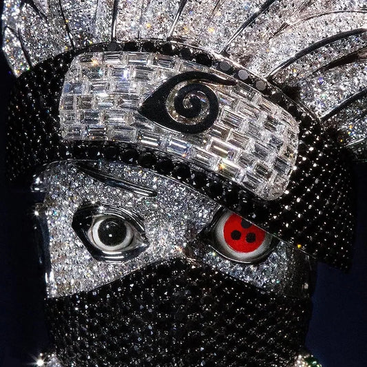 A close-up of a highly detailed, rhinestone-covered mask or decorative face piece with black base, silver crystal patterns, and two stylized eyes including one red-and-black pupil and one clear spiral eye.