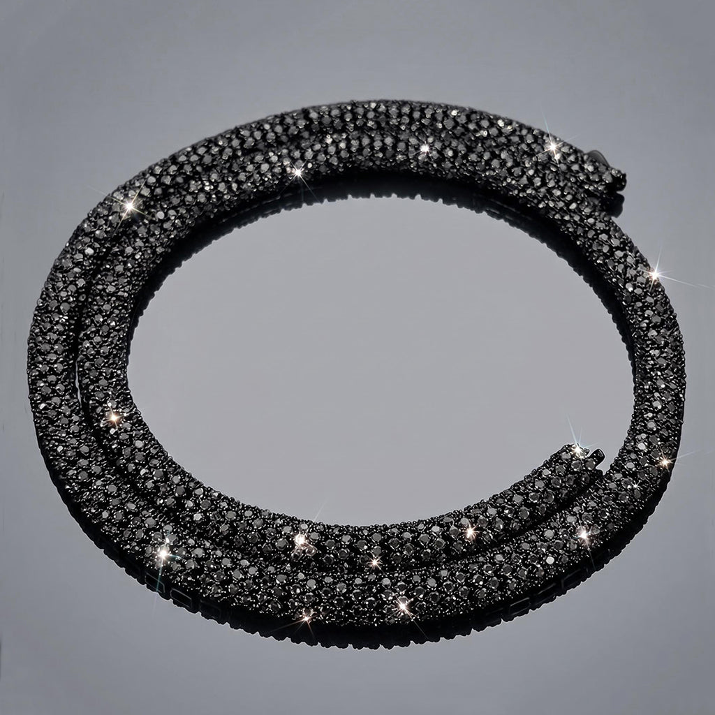 A black pave-set snake necklace with a textured scale pattern, photographed on a reflective gray surface.