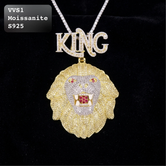 A lion head pendant necklace with a gold textured mane, a silver and white stone face, red gem accents in the eyes and mouth, and a silver 'KING' letter pendant on a silver chain, displayed on a black background.