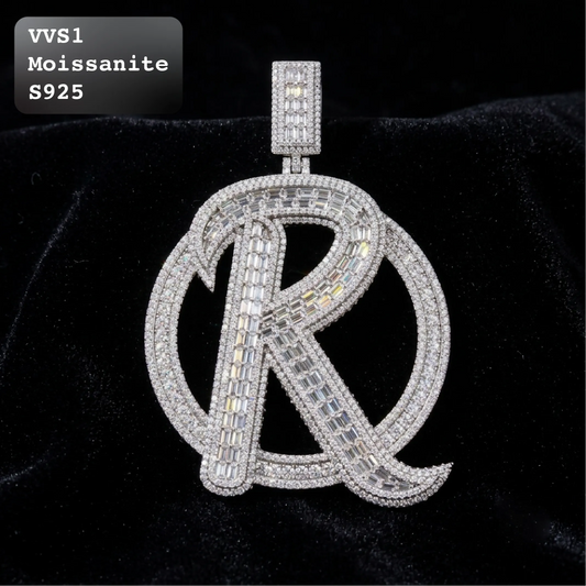 A large letter 'R' pendant encrusted with clear stones, displayed on a black velvet background. A text overlay in the top-left corner reads 'VVS1 Moissanite S925'.