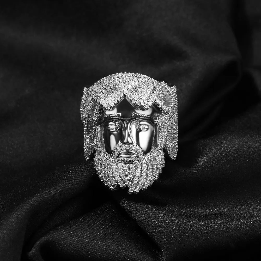 Silver face-shaped jewelry piece with beaded details on a black fabric background