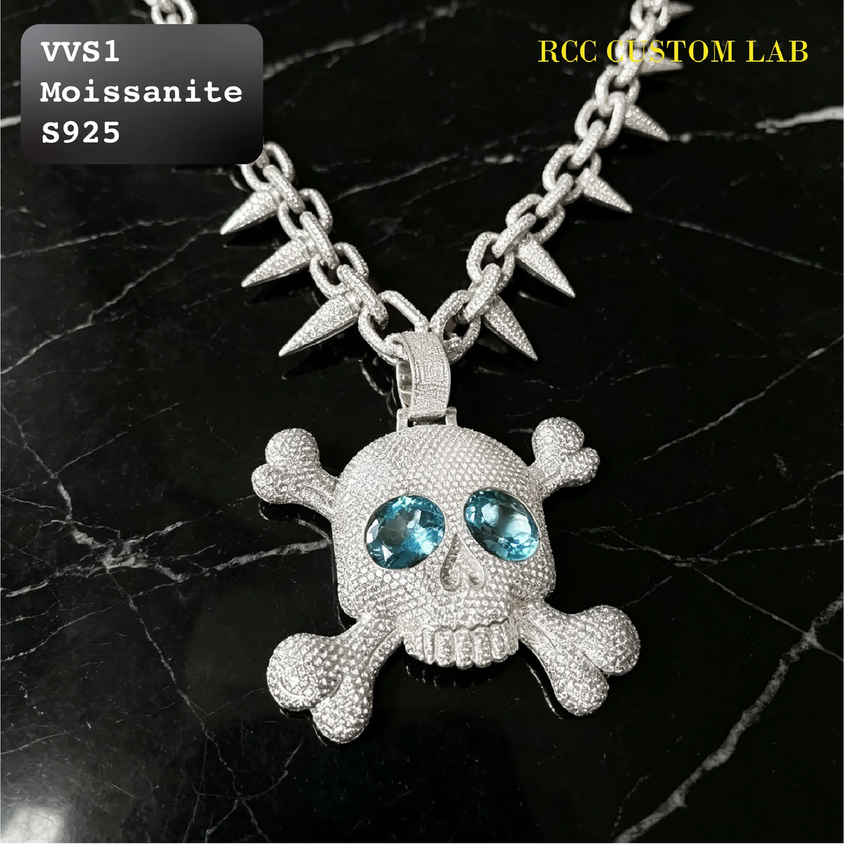 A silver-toned skull and crossbones pendant necklace with spiked chain links, displayed on a black marble background. The skull features prominent blue gemstone eyes.
