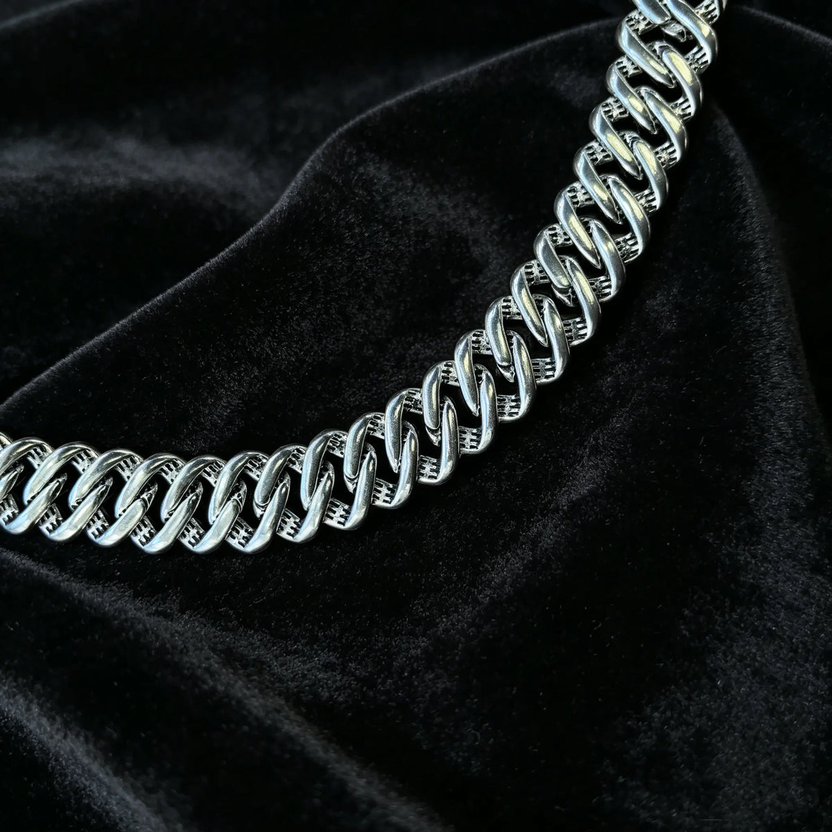 Macro close-up of plain polished silver cuban link chain, smooth hollow metal links without stones, minimalist heavy hip hop necklace texture view