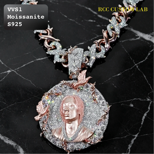 A custom Moissanite necklace featuring a circular pendant with a rose gold bust portrait of a man, surrounded by sparkling clear stones, displayed on a black marble background. The chain is also paved with clear stones and features rose gold accents.