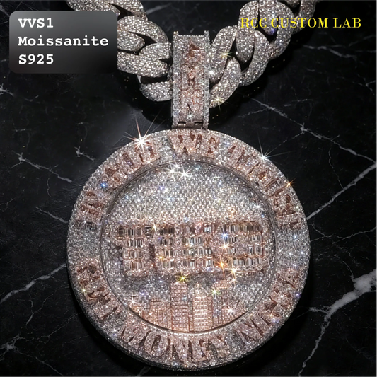 A close-up of a large round pendant necklace covered in sparkling stones, featuring a rose-gold-toned center with a building illustration and a silver-toned outer border with text. A matching chain is partially visible at the top.