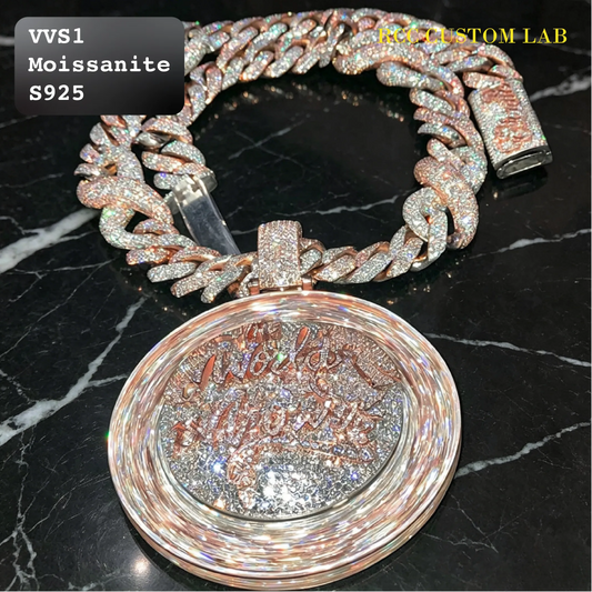 A close-up of a custom Cuban link chain bracelet and matching round pendant. The chain and pendant are heavily embellished with sparkling clear stones in a rose gold-toned setting, with a glittery silver interior inside the pendant.
